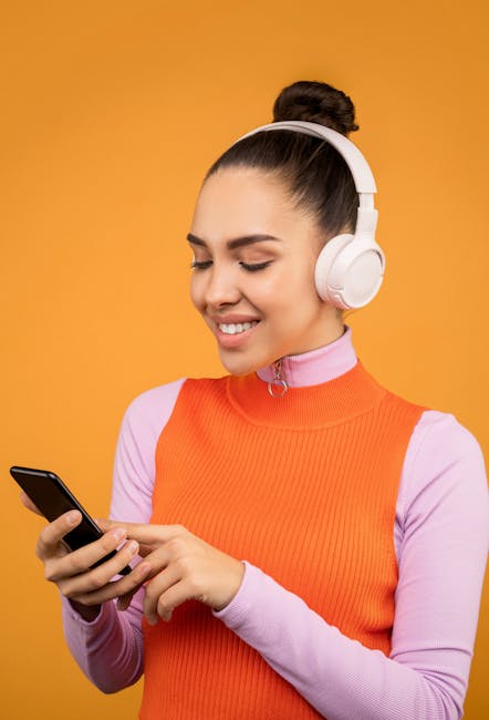 A woman in vibrant attire enjoying music on headphones with a smartphone.