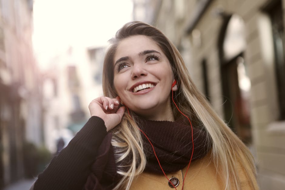 Joyful young woman enjoying music with earphones on a bright day in the city.